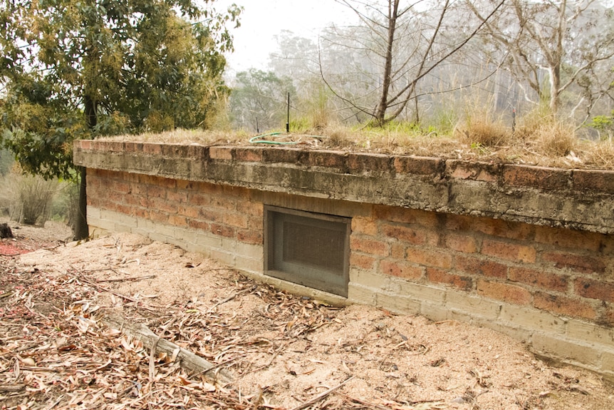 A small brick building build into a hillside with concrete roof and small window