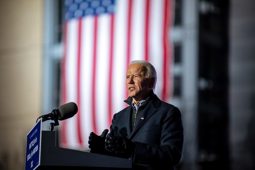Joe Biden stands at a lecturn in front of an American flag as he gives a speech in Pittsburgh