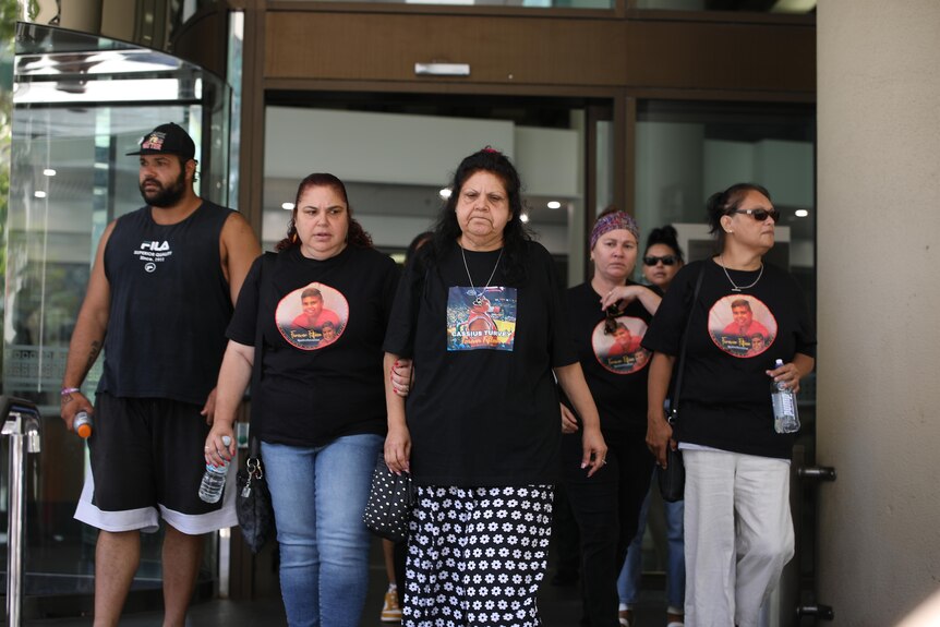Indigenous people wear black shirts picturing Cassius Turvey as they leave court