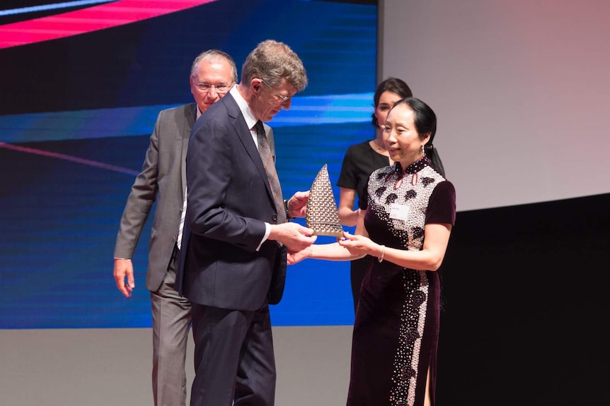 A man and a woman receiving an award on a podium