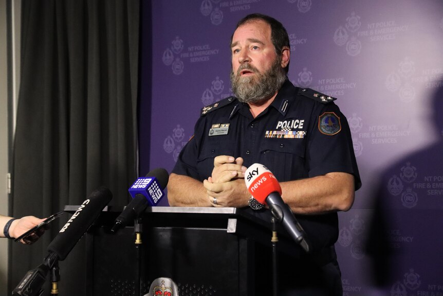 NT Police Senior Sergeant Danny Bacon stands at a lectern at a press conference.