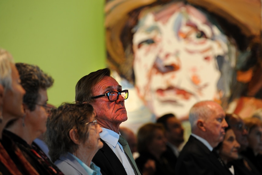 man at memorial service with art in background