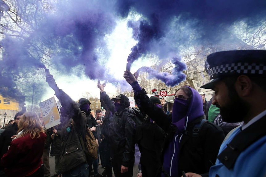 Protesters let off purple smoke.