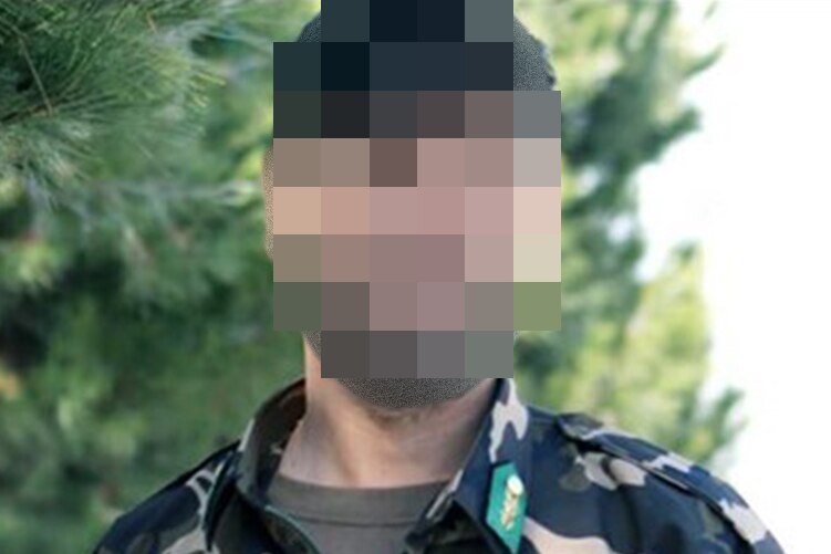 An Afghan man with his face blurred dressed in military fatigues