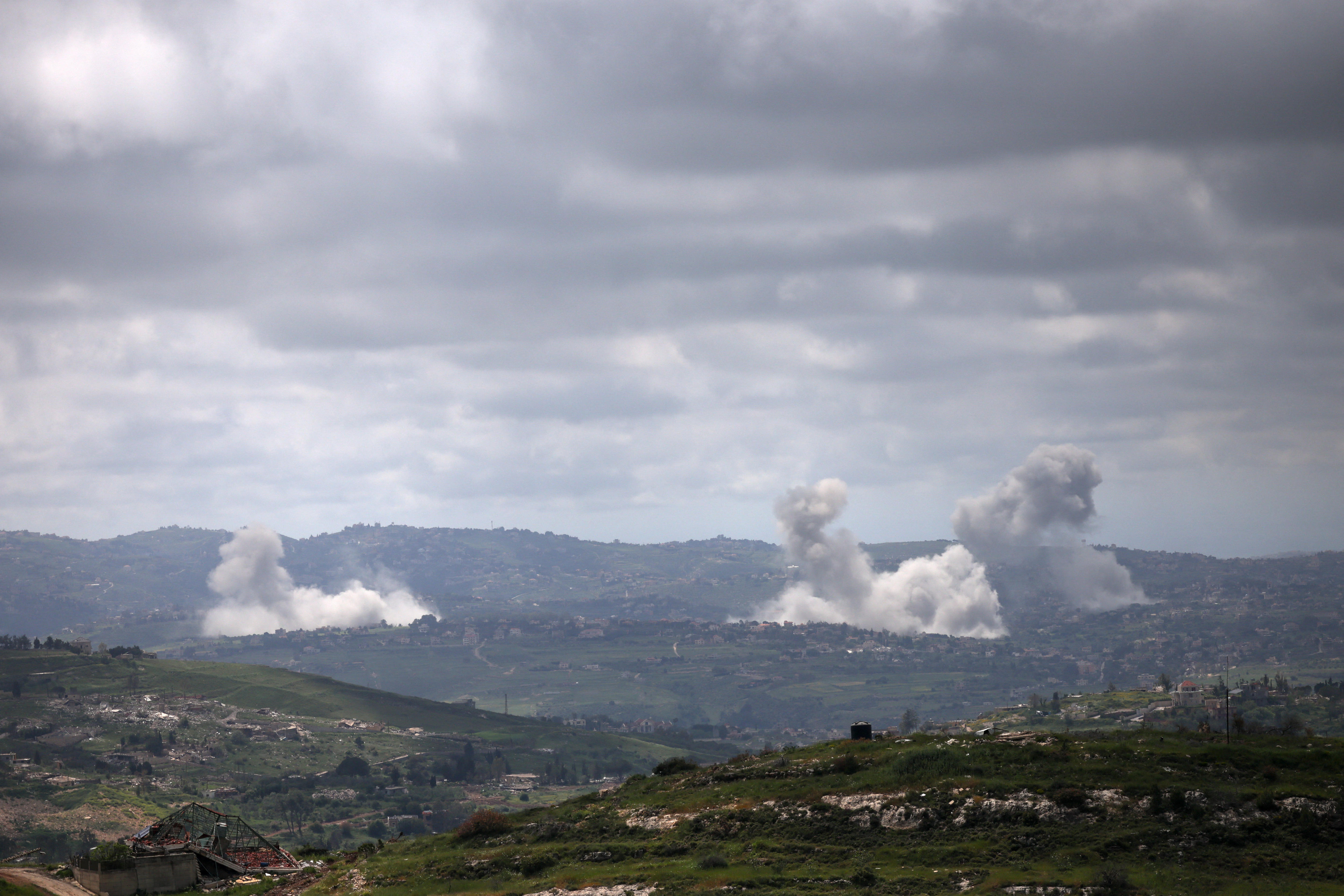Smoke rises over a mountainous field.