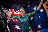 An Australian gymnast tears up as she holds an Australian flag behind her back after clinching a gold medal.