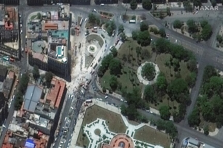 A satellite image of the streets of Havana, Cuba, where vehicles and people crowd near a damaged building and rubble on street.