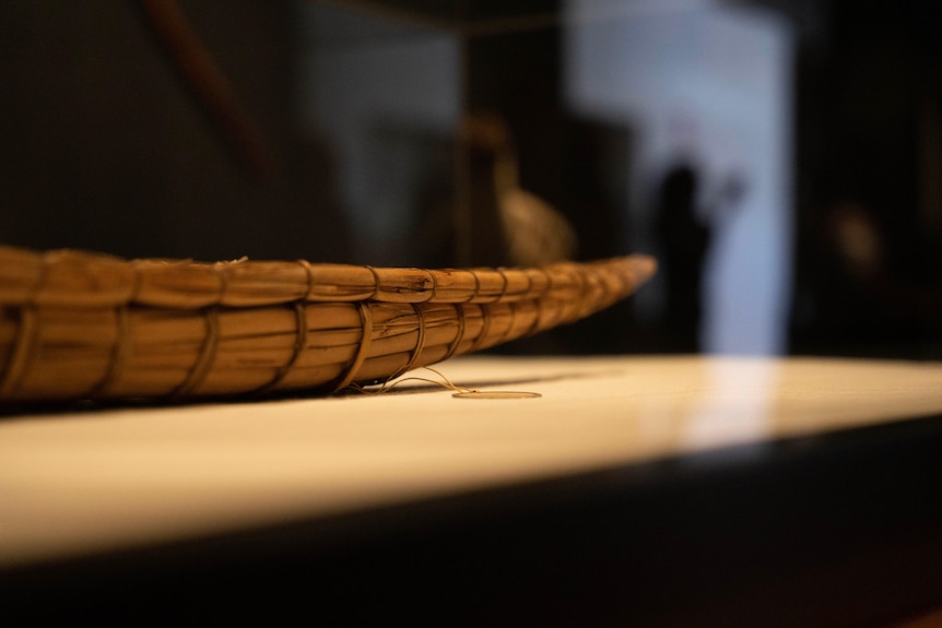 A small model canoe is seen on a stand, made of rushes.