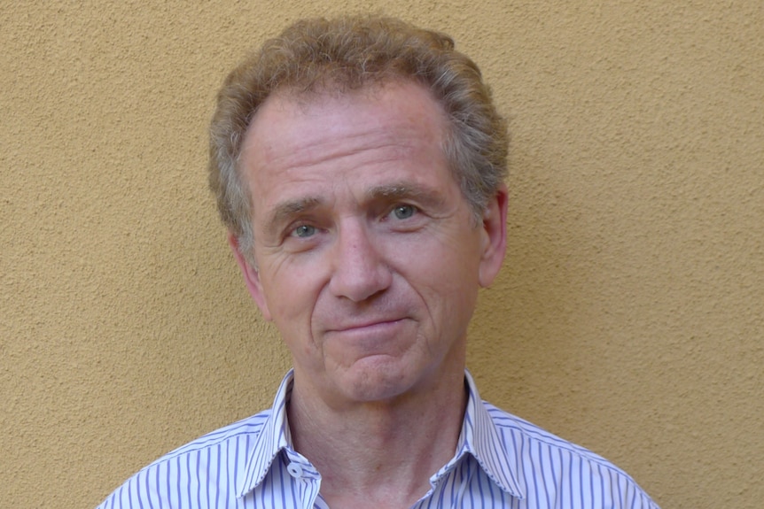 A middle aged man with graying hair smiling at the camera.