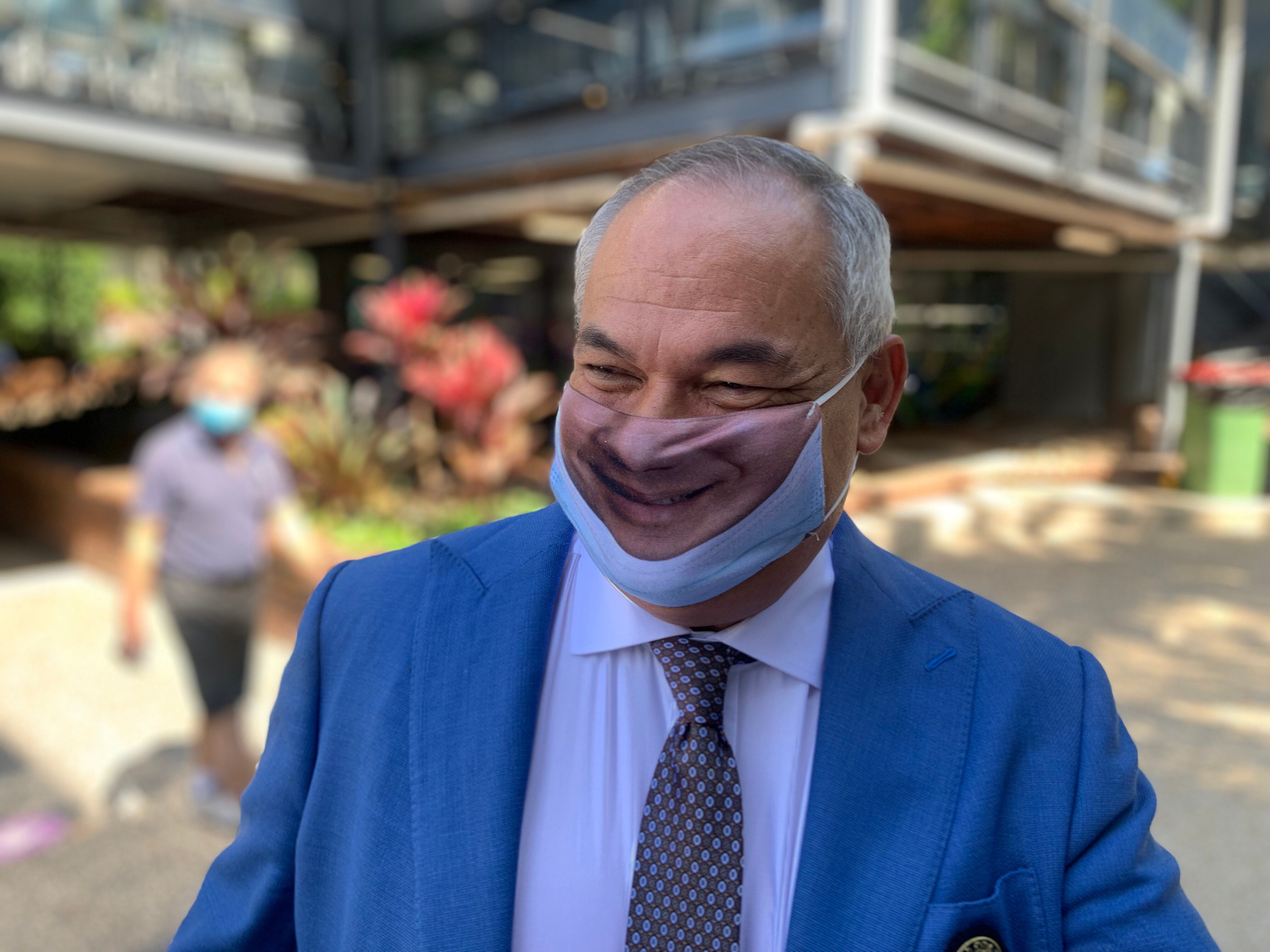 Man wearing a face mask with an image of a smiling mouth printed on the front.