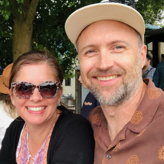 Still from Jemma's story, two people smiling in a photo, one wearing sunglasses and the other wearing a hat