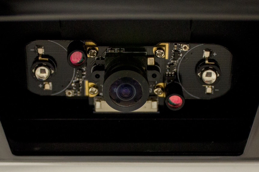 A camera-like sensor screwed into a black mount