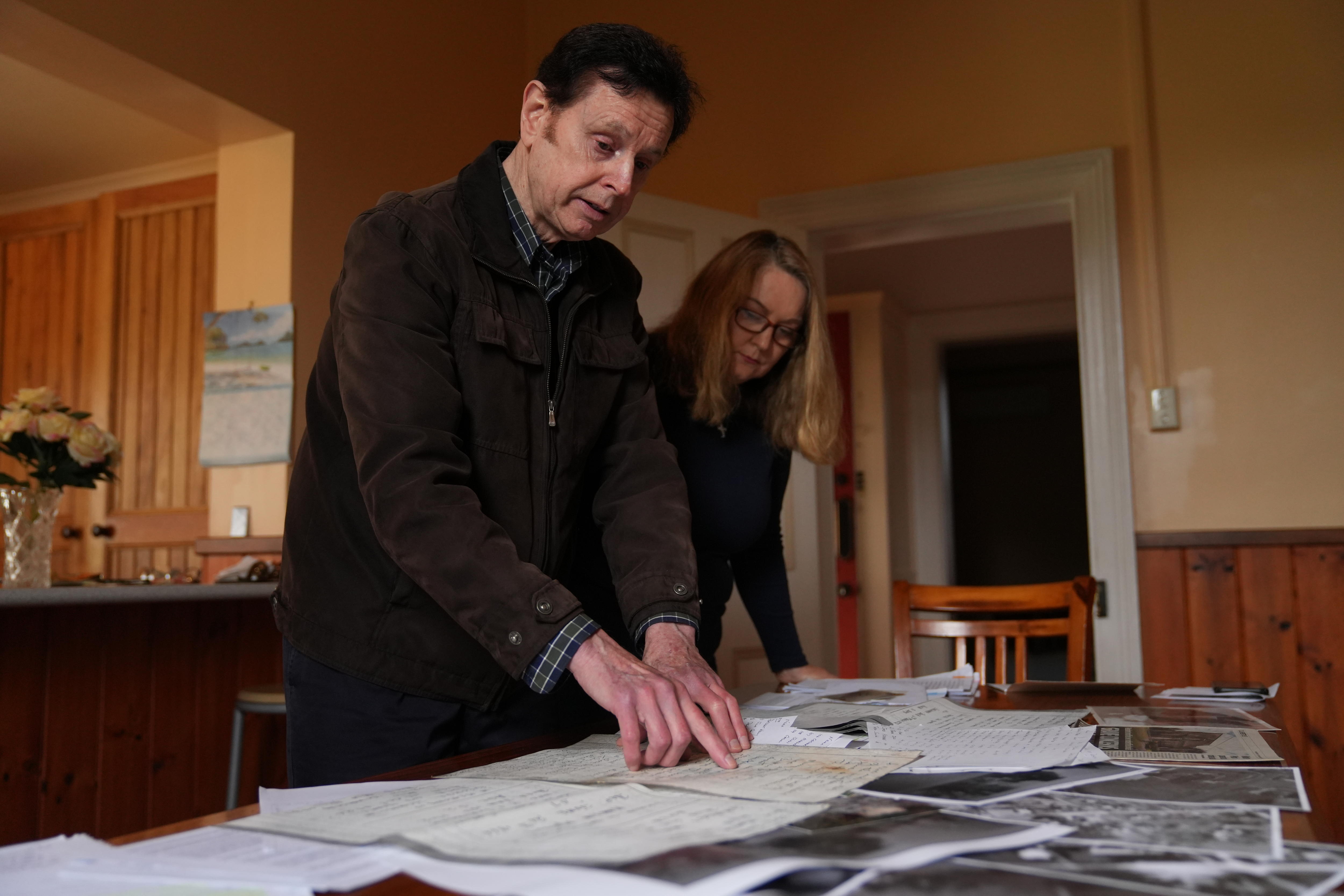 A table with documents all over it, which Mark Butson is pointing to