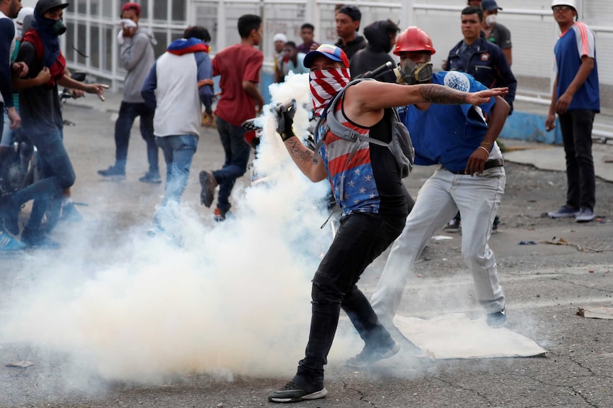 A man with his face covered with a smoke bomb in his hand