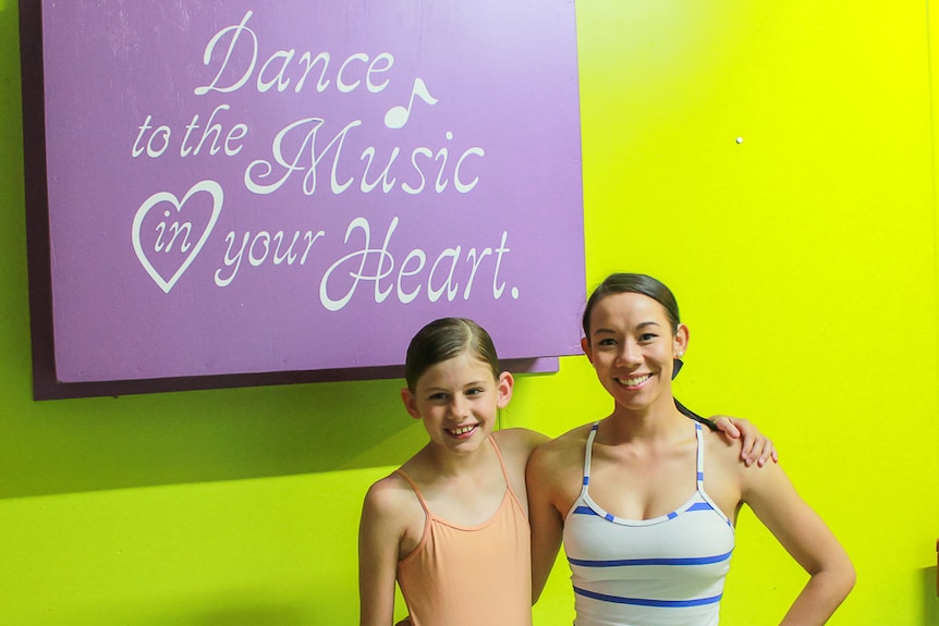 Julie Creek dance teacher Amy Thieme stands with a student in front of the dance school sign.