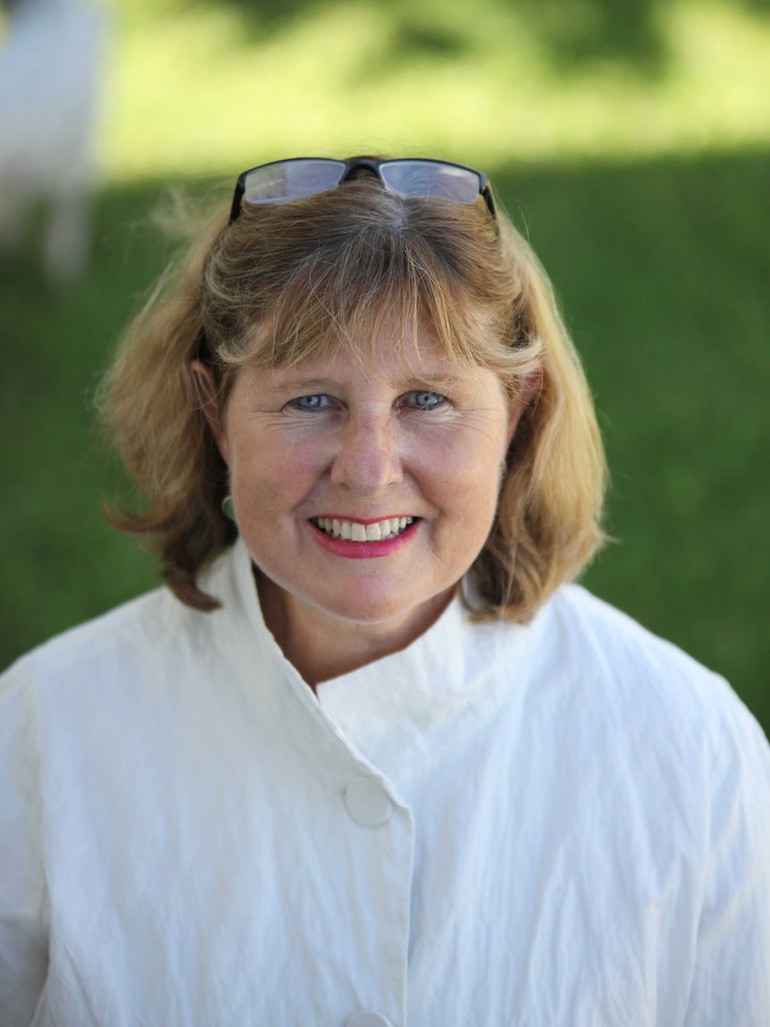 Woman in white blouse with light shoulder light coloured length hair with sunglasses on her head