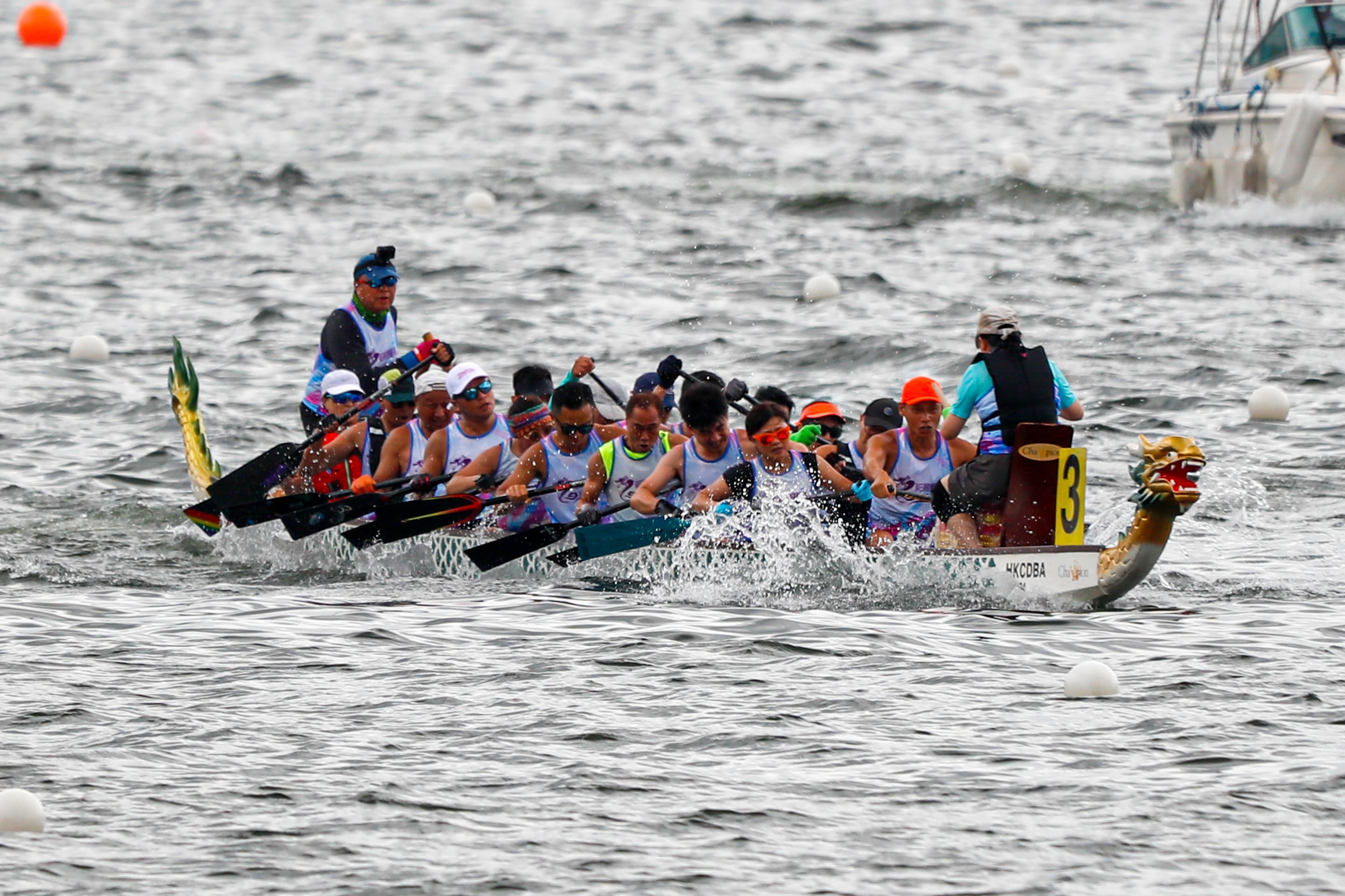 Uma equipe de barcos-dragão desce um rio enquanto puxa os remos atrás deles e os tira da água.
