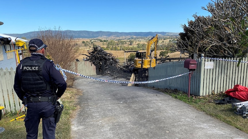 A police officer watching over the scene of a house fire.