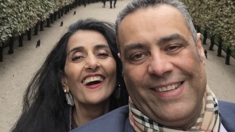 A selfie of Ayman and Samiha, both smiling warmly, a park pathway visible behind them.