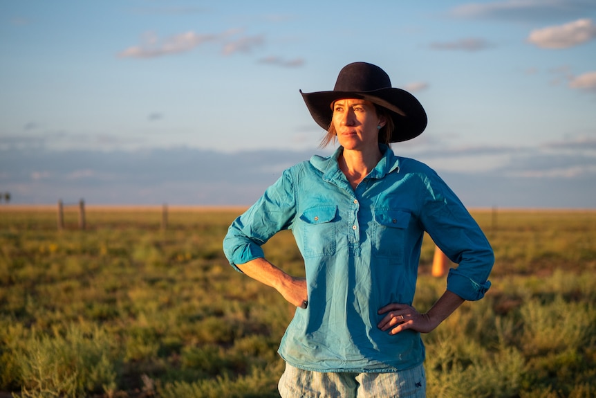 Meg Morton with big hat on standing in a paddock at sunset, near Winton, November 2022.