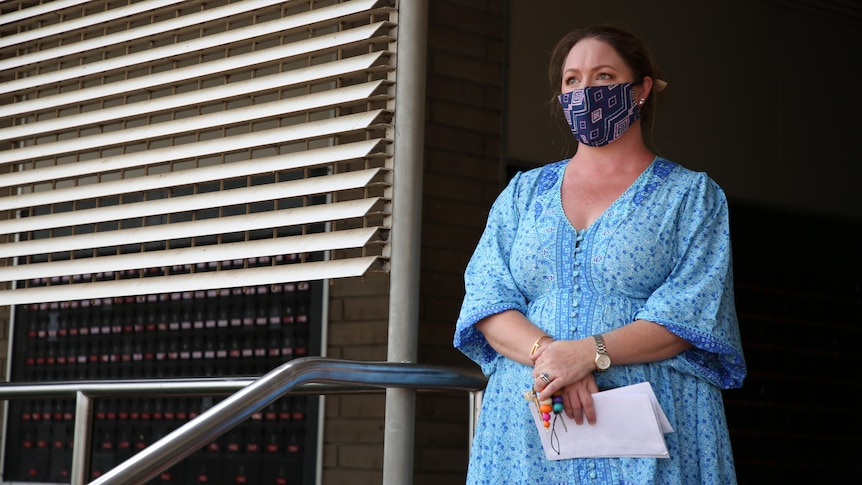 Katherine business owner Rebecca Beaumont stands outside a building wearing a mask.