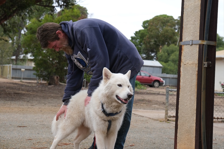 A man with a white dog on a street.