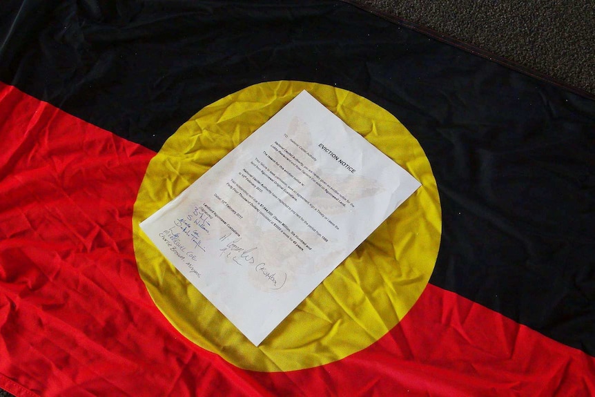 An eviction notice in the middle of an Aboriginal flag.