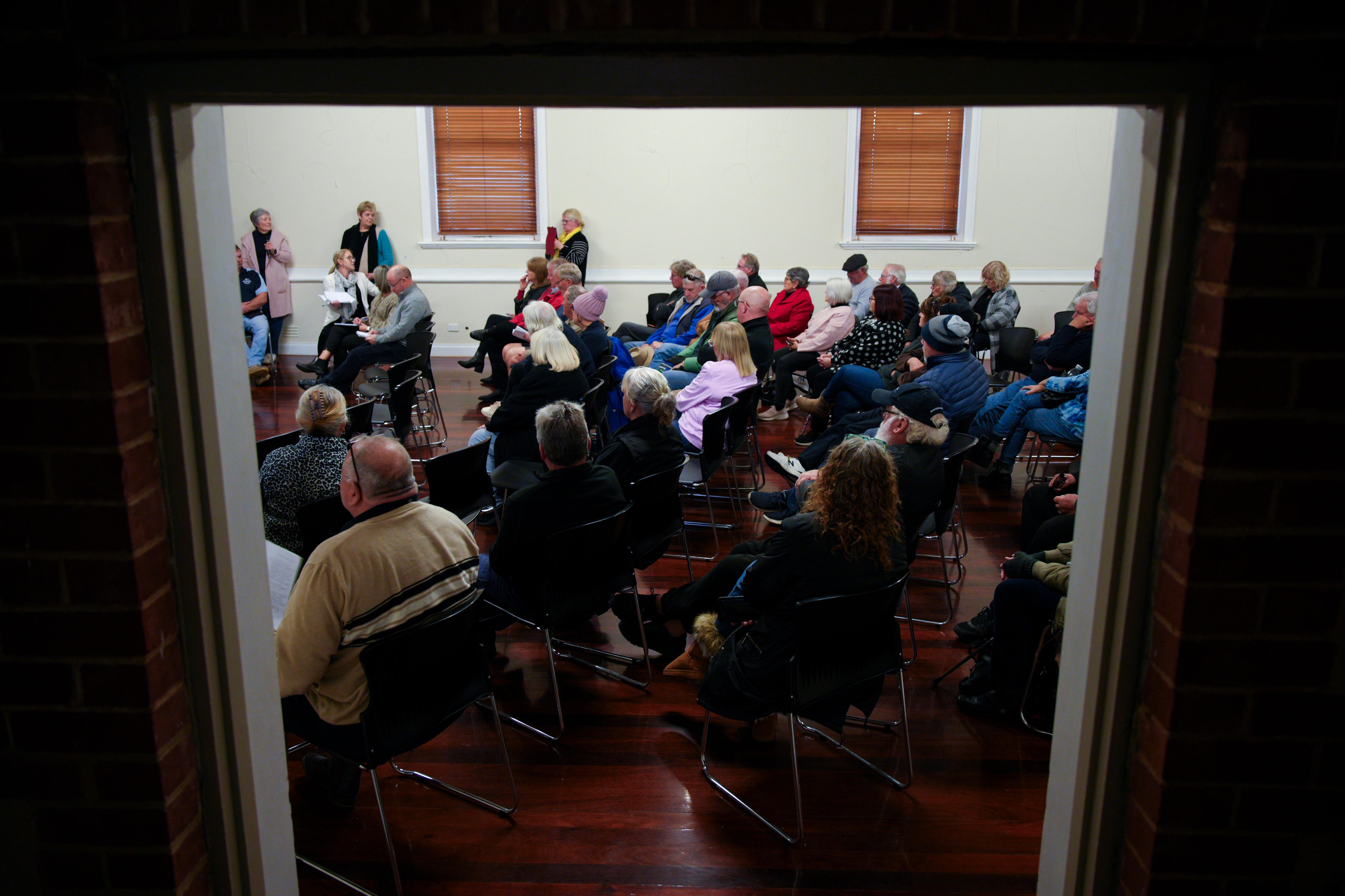 Un grupo de personas se sienta en sillas, mirando hacia un orador
