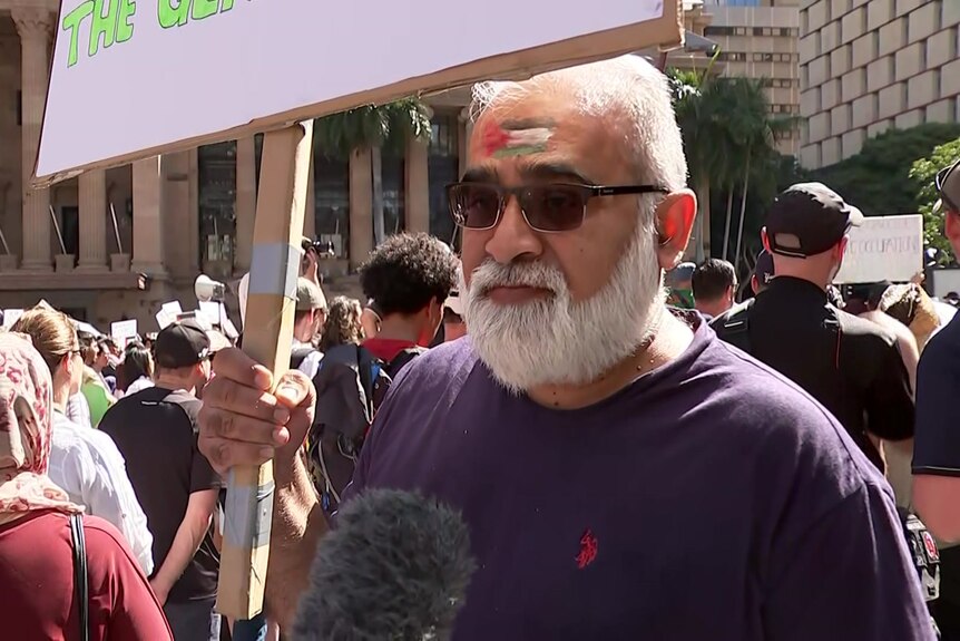 a man holding a placard in support of palestinian people at a rally in brisbane on saturday october 21