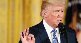 Donald Trump gestures with his right hand while speaking into a microphone in the east room