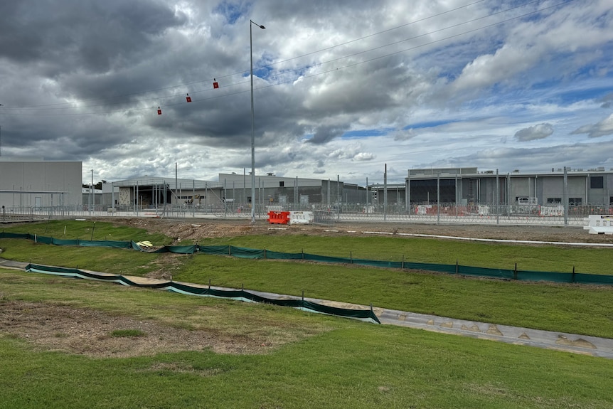 A huge, under-construction prison complex beneath a cloudy sky.
