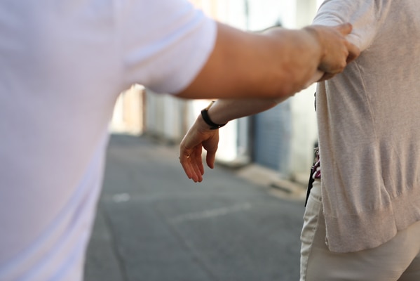 A man grabbing a woman's arm as she walks away from him.