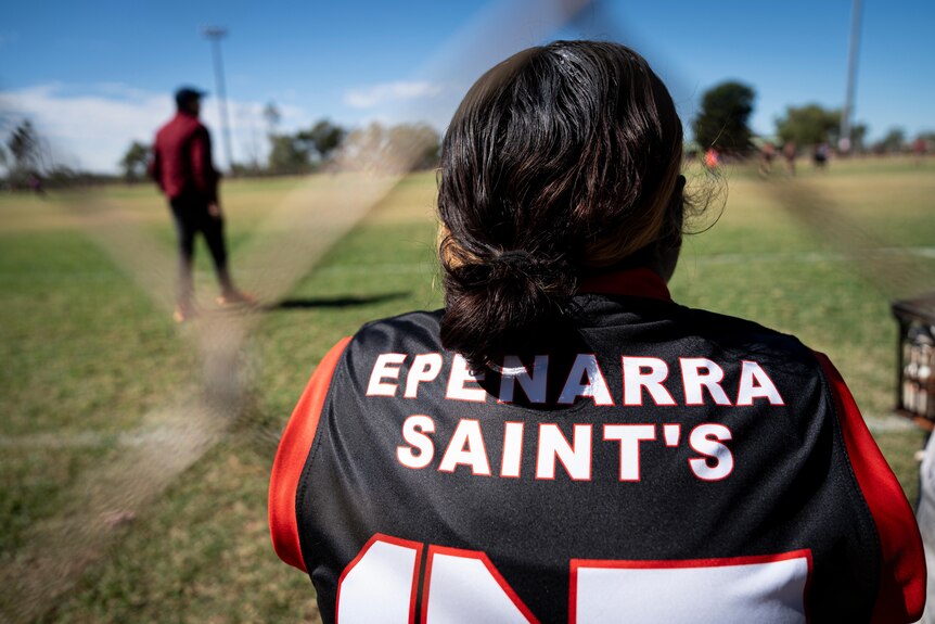 A photo showing Epenarra Saints players watching on with their shirt number on their back.