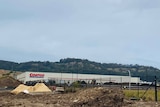 A warehouse with a Costco sign, surrounded by earthworks and a metal fence.