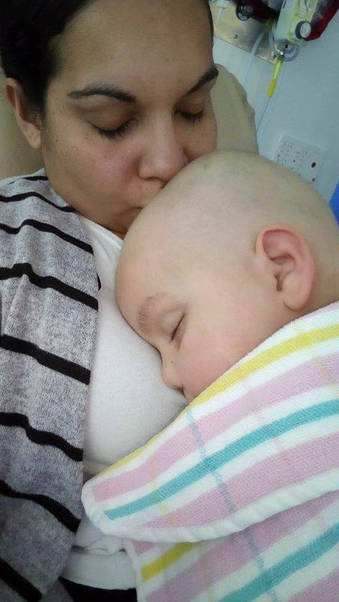 A mother cuddles her baby in a hospital bed