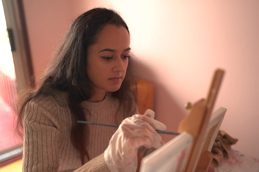 A woman paints on a canvas.