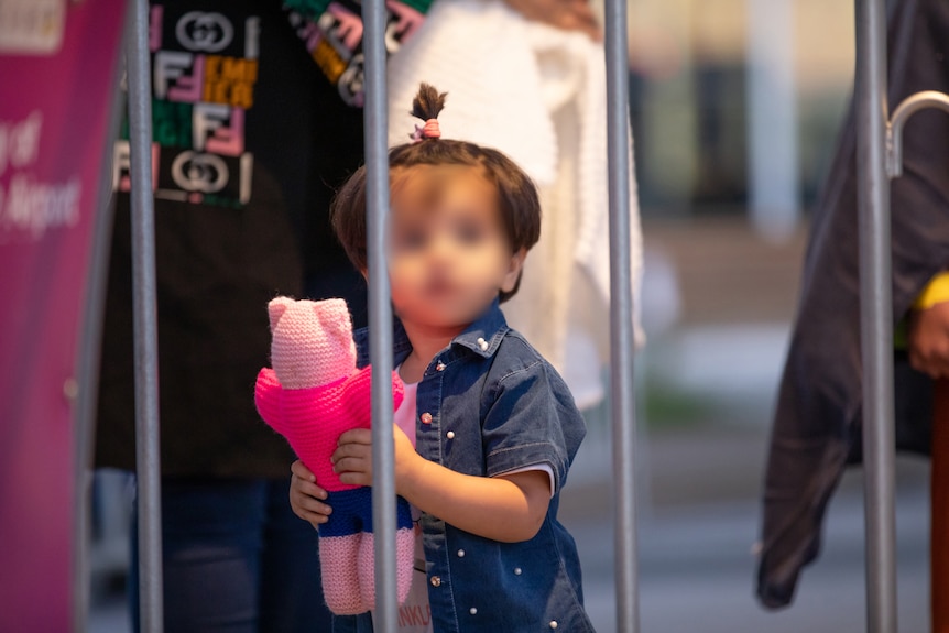 A small child, deidentified, holds a teddy bear.