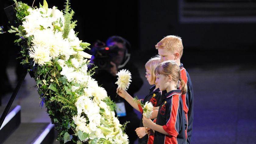 Solemn and uplifting: Children place flowers in a wreath during the service.