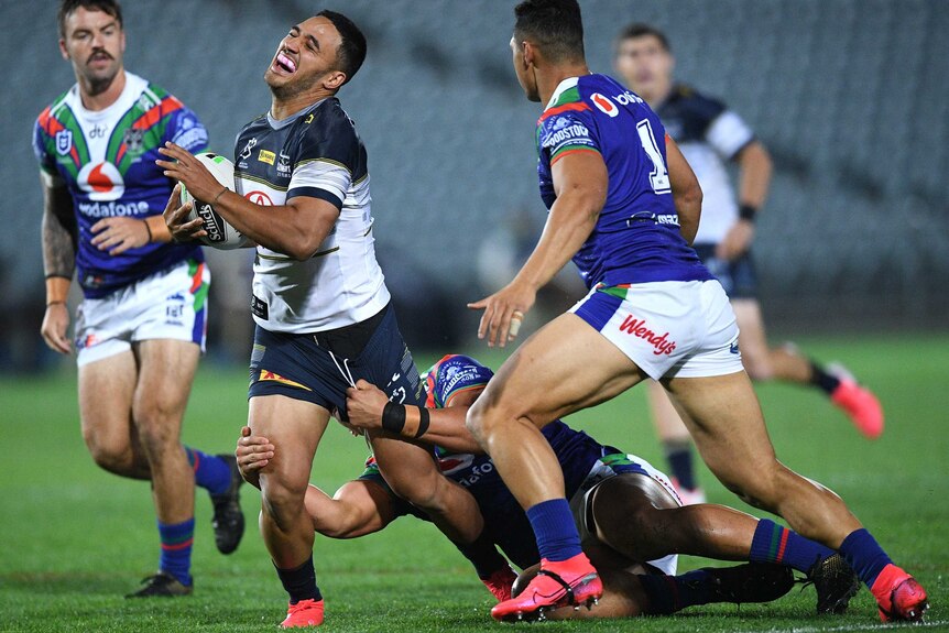 An NRL players grimaces as he gets caught in a tackle.