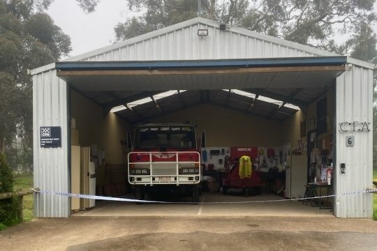 Door on tin shed of fire station is open, showing the red CFA fire truck and inside the station. 