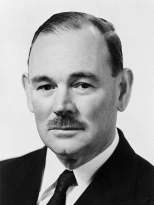 A man with a moustache wearing a black suit and tie.