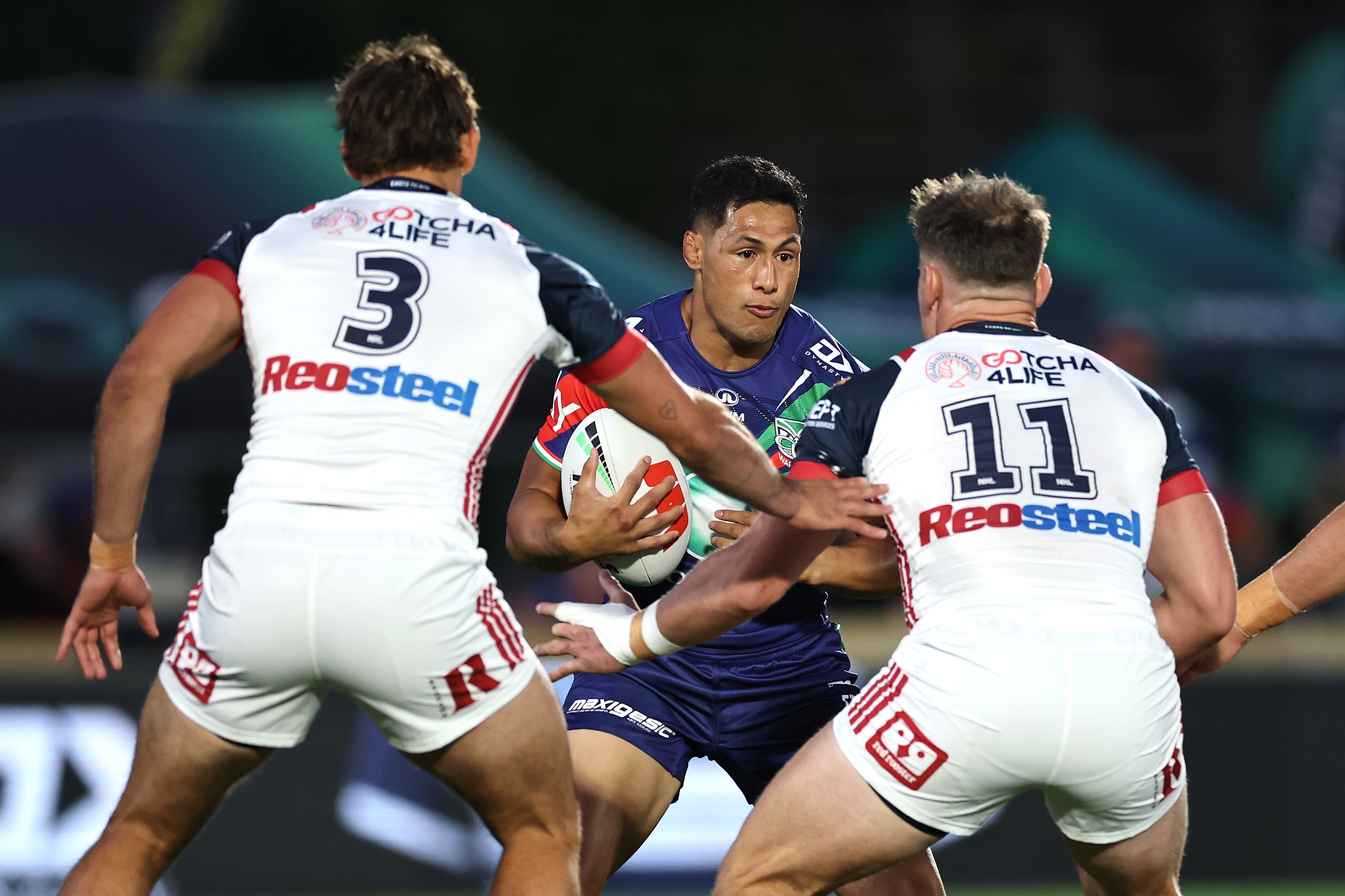 Roger Tuivasa-Sheck runs towards Roosters defenders Billy Smith and Angus Crichton during an NRL game.