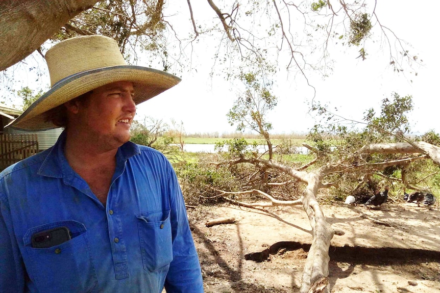 Tim McGee surveys the damage, a big tree branch beside him.