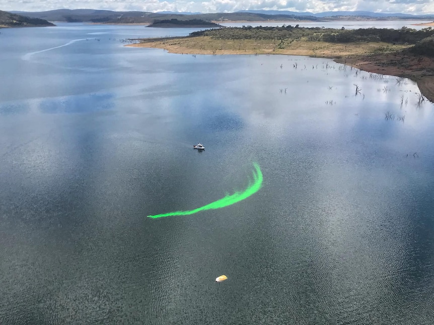 An aerial shot of a lake with a green streak.