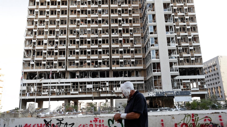 A man bandaged up walking past destruction seen after a massive explosion in Beirut, Lebanon.