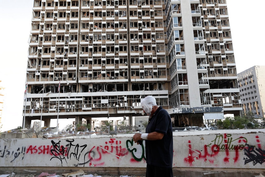 A man bandaged up walking past destruction seen after a massive explosion in Beirut, Lebanon.