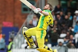 David Warner leaps high in the air, preparing to push his right arm, which is carrying his helmet, further into the air.