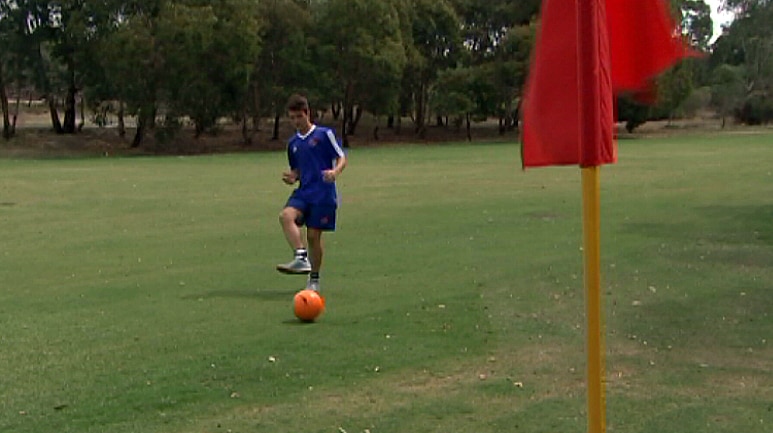 A FootGolf players kicks balls towards the whole.