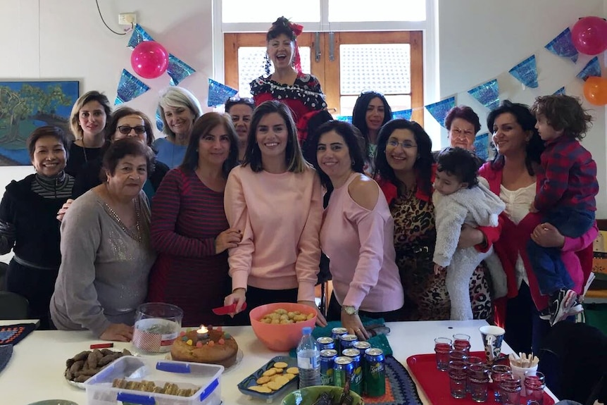 A group of women from different ethic and cultural backgrounds stand around a table laden with food