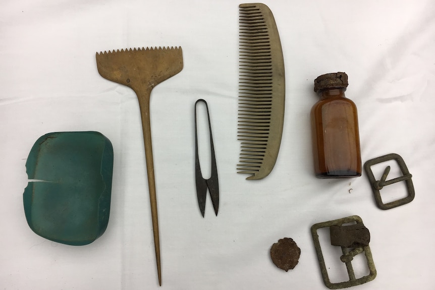 Old artefacts including a comb, small glass bottle and belt buckle